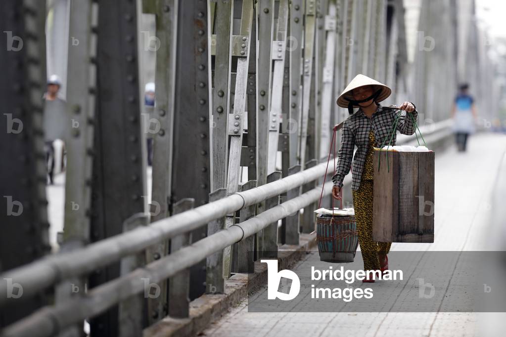 Vietnamese woman carrying baskets on the famous Trang Tien Bridge, Hue, Vietnam, 2019 (photo)