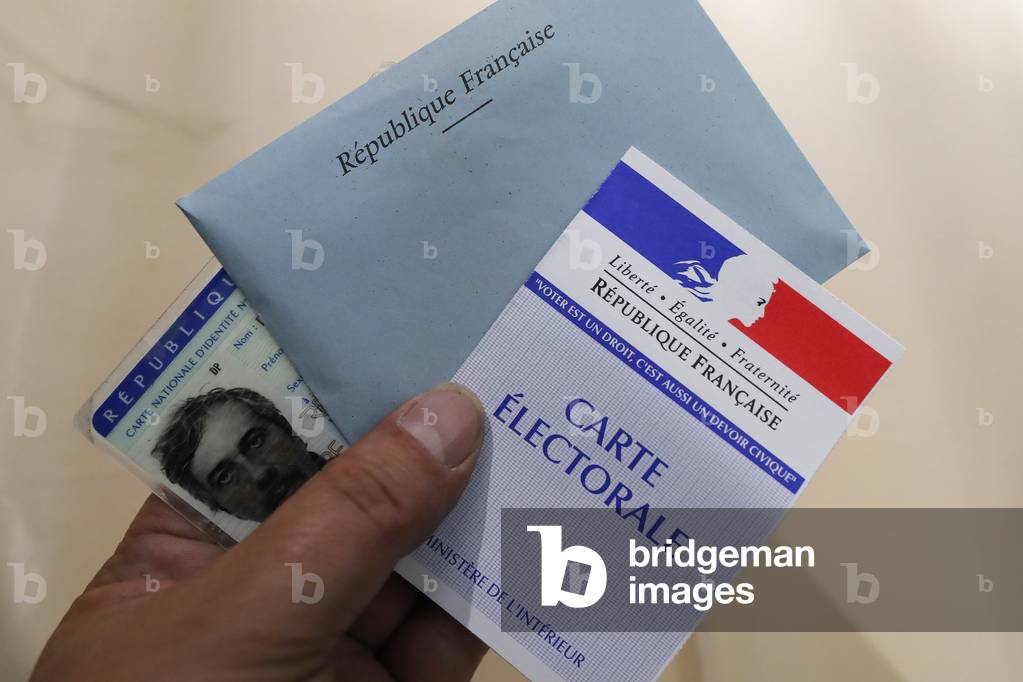 Hand of a person casting a ballot at a polling station during voting in France (photo)