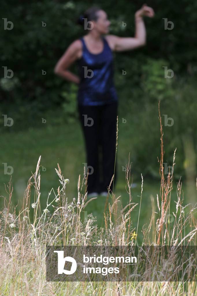 Woman practicing Qi Gong or Tai Chi exercise   in nature.  France.