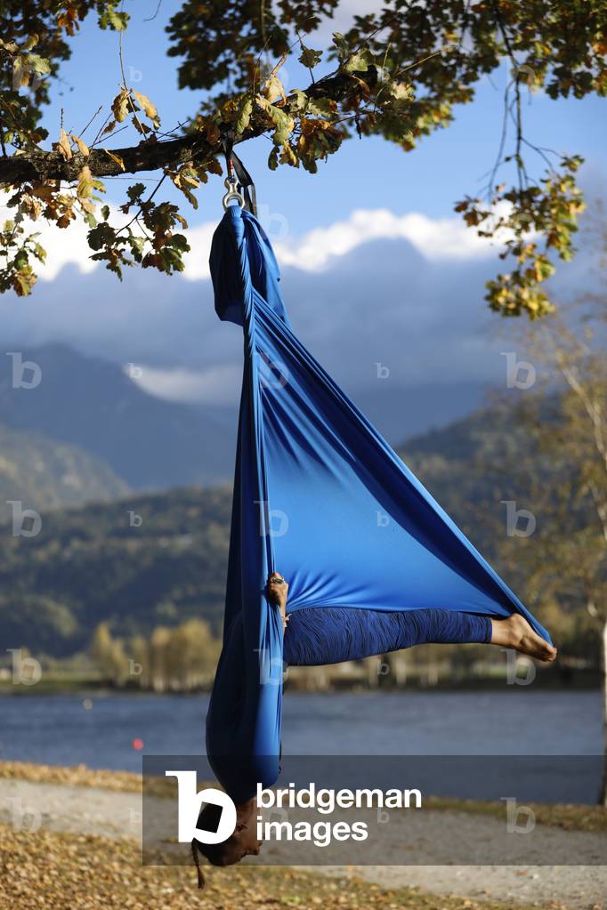 Woman doing pose of aerial yoga using hammock outdoors. Saint-Gervais. France