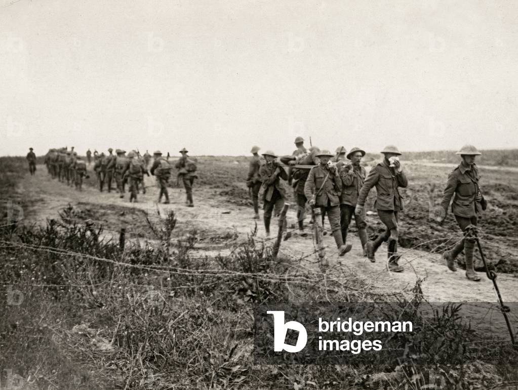 Fresh troops march to the front line as wounded comrades are carried back, Western Front, 1914-18 (b/w photo)