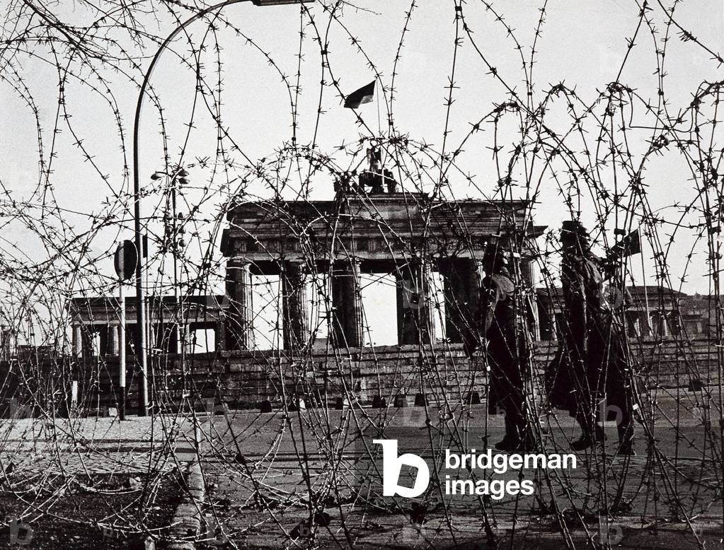 Berlin Wall: Two policemen patrolling near the Brandenburger Tor wall (Brandenburg Gate), Germany. Photograph.