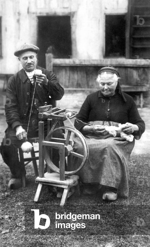 Man helping his wife to spin with a spinning wheel (rour a spinning wheel).