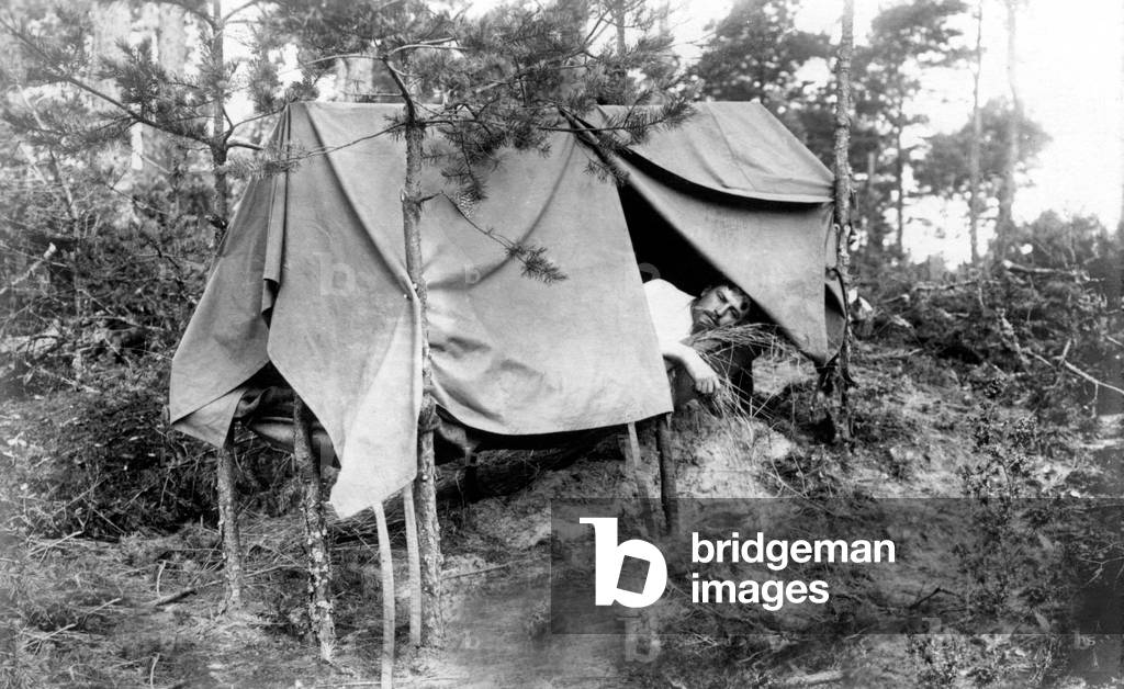 Camping in nature: Man sleeping under a tent brought by himself. Photography around 1912