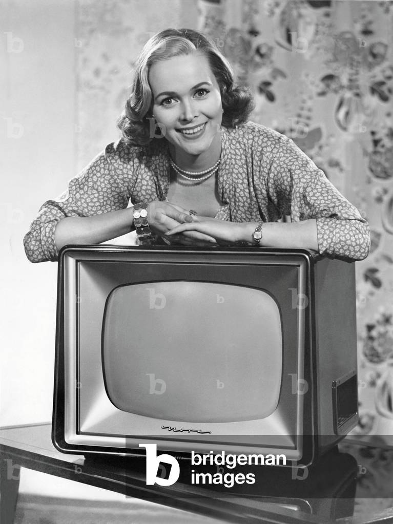 The beginning of the consumer society: woman posing over a television set. Photography around 1955.