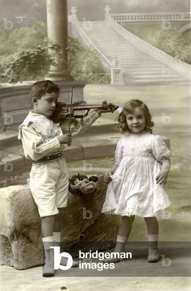 Young boy playing violin for his young friend. photography around 1910
