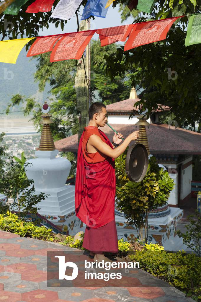 Tibetan Buddhism; monk in a red robe beating the gong; Kharbadi Gompa; Phuentsholing; Kingdom of Bhutan; South Asia; Asia