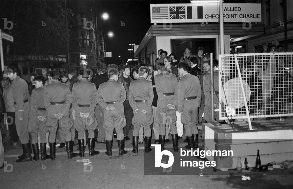 GDR border guards aline at Checkpoint Charlie in Berlin on the night of 9 November, 1989 (b/w photo)