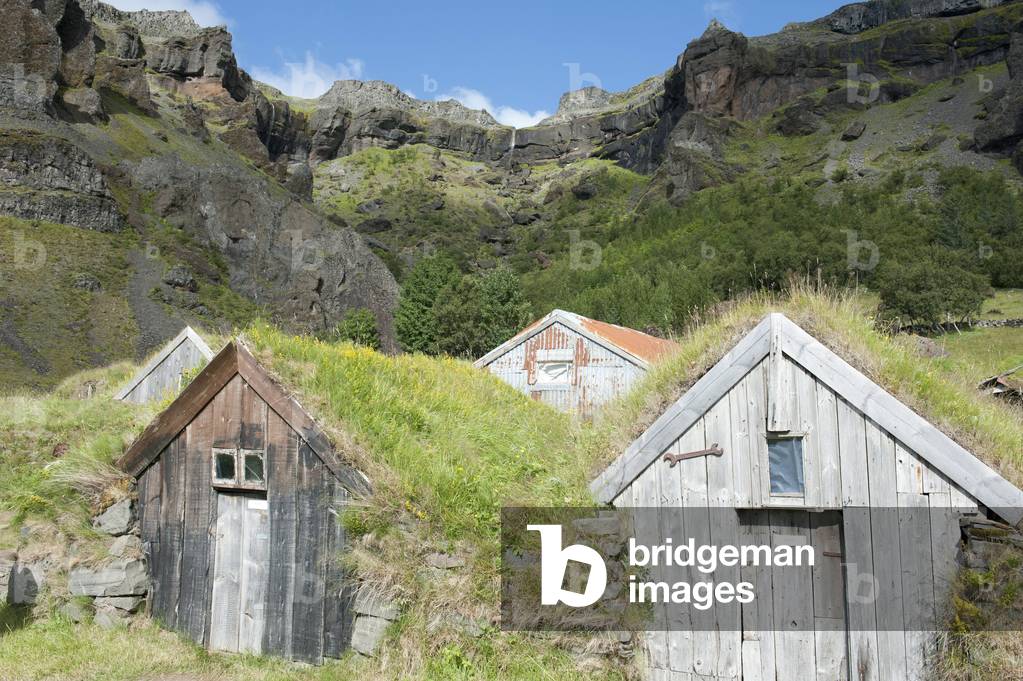 Old sheds with sod or turf roofs underneath mountainside; Nupstadur; Nupstadur; Iceland; Scandinavia; Northern Europe; Europe