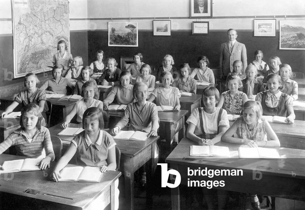 Class of a girls' school with their teacher and a geographic map of Germany hanging at the back of the room. Photography around 1920