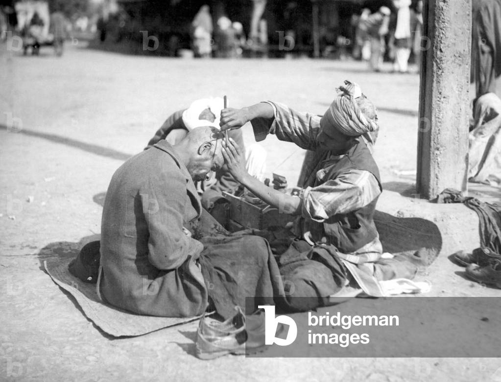 Small street metier: the hairdresser, a man gets shaved his head, Tunis, Tunisia. 1920 approximately Historic photograph, hairdresser, around 1920, Tunis, Tunisia, Africa