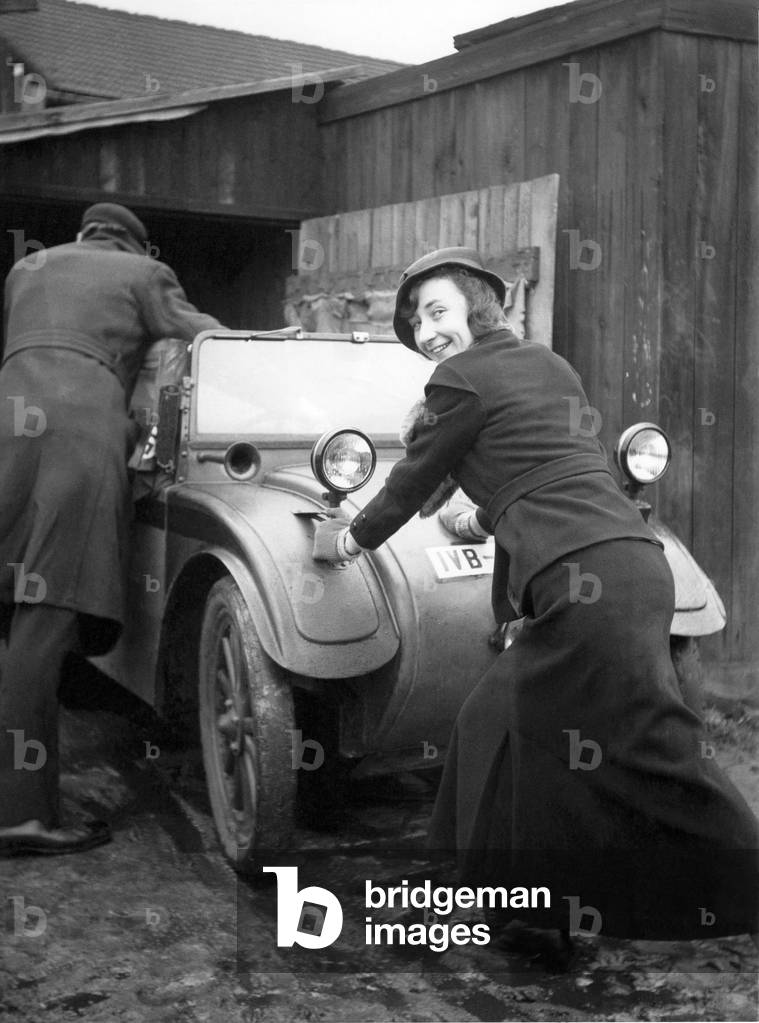 Woman pushing a car. Photography around 1925
