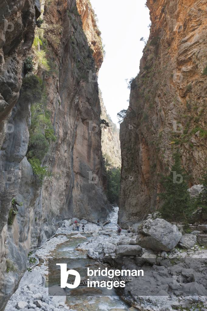 Steep cliffs rise up above the rocky bed of a stream; several hikers; boardwalks; 3rd Gate; Iron Gate; view towards the south; Samaria Gorge National Park; near Agia Roumeli; Crete; Greece; Europe