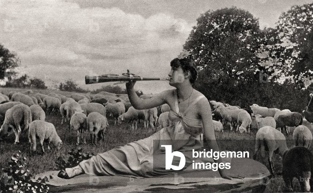 A shepherd's joilie surrounded by a herd of sheep in a bucolic decor plays the flute. Postcard from the beginning of the 20th century