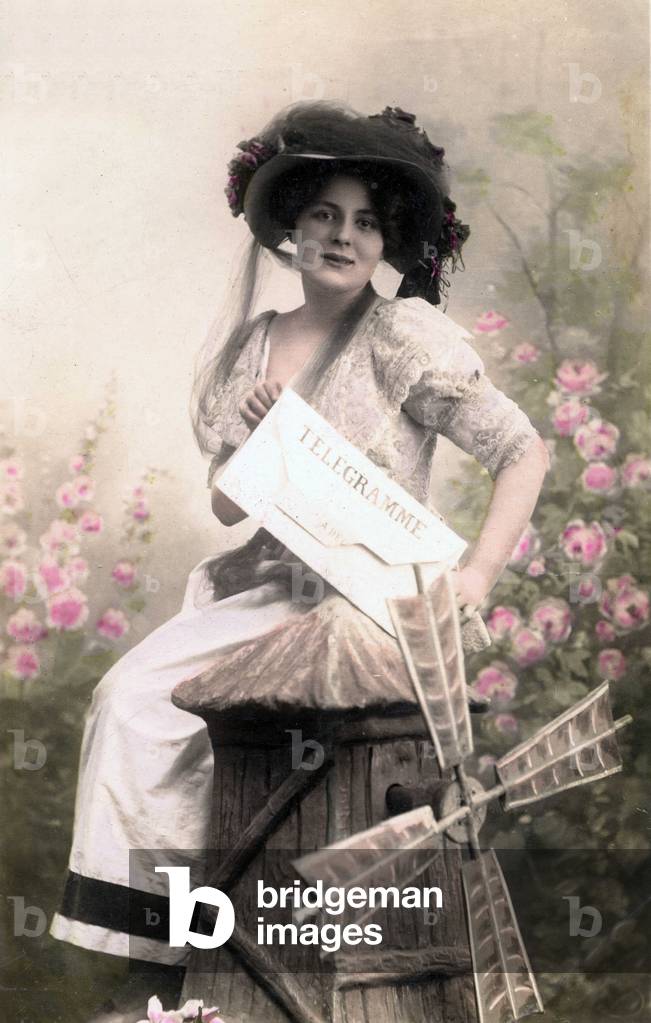 A young woman dressed elegantly, sitting on a miniature mill presents a telegram. Postcard from the beginning of the 20th century.