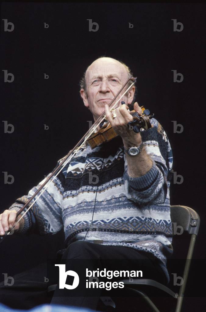 Member of The Dubliners sitting playing the fiddle at Fleadh 1996. Irish folk music. Rock.
