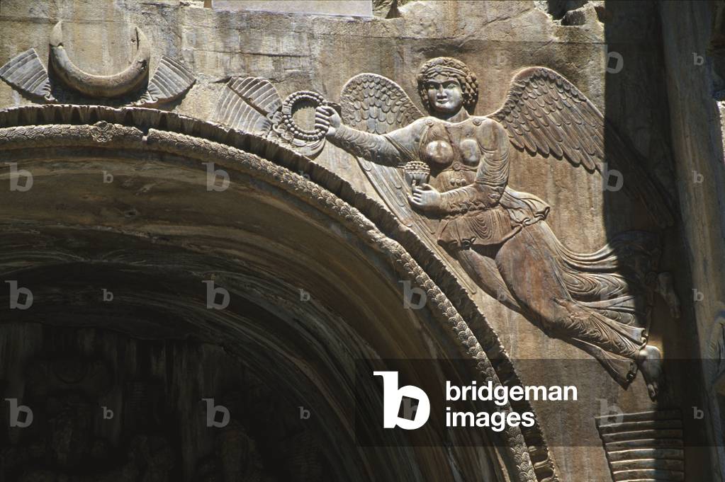 A winged figure holding a royal crown at the entrance to the Sassanian grottoes of Taq-e Bostan (photo)