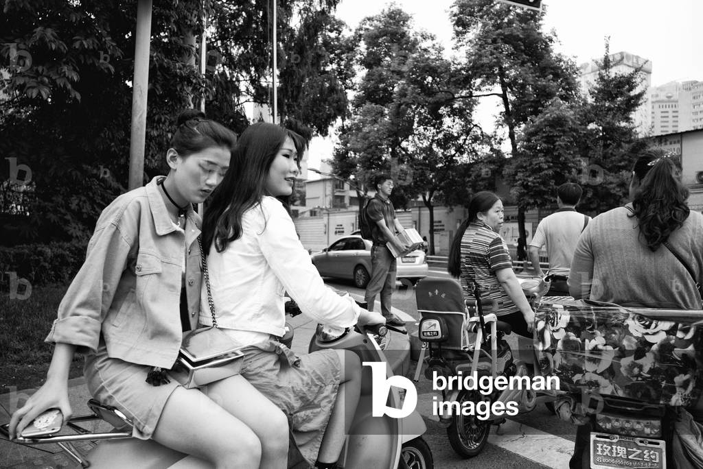 Young girls on bike in traffic Chengdu, China (b/w photo)
