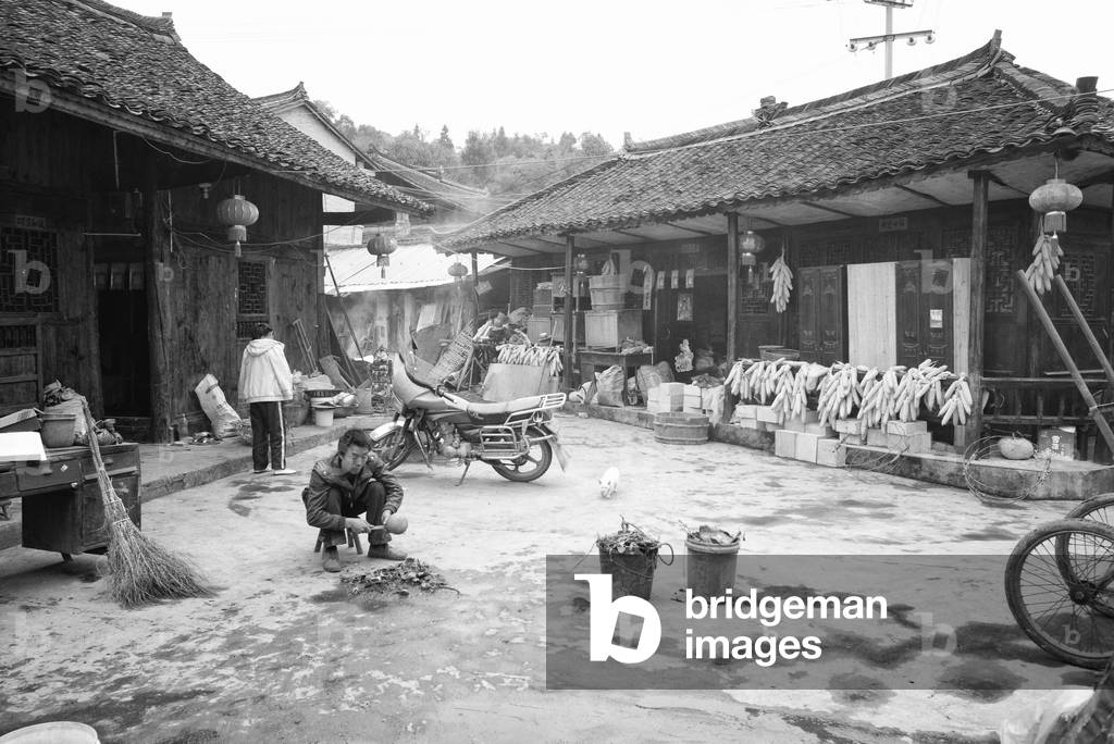 Man lights fire in his courtyard, Yibin, China (b/w photo)
