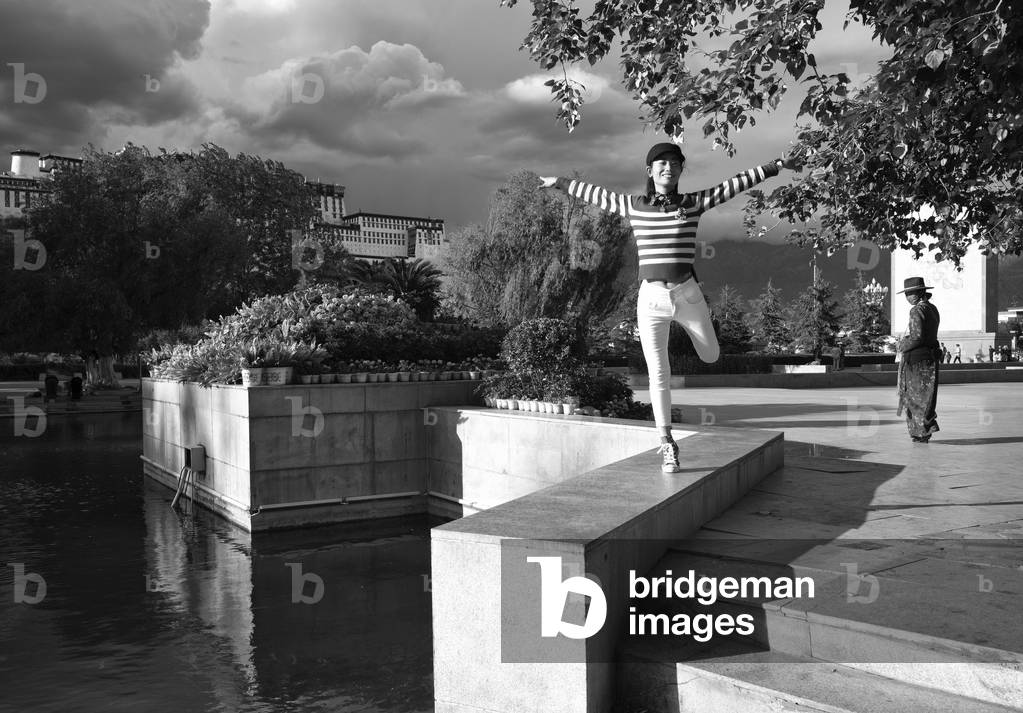 Young girl happy and dances in front of Portala Palace in Lhasa, Tibet (b/w photo)