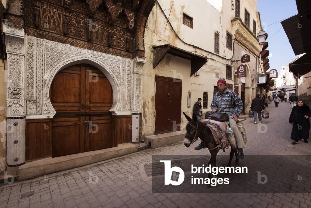 Man riding a donkey in the street in Fes, Morocco (photo)