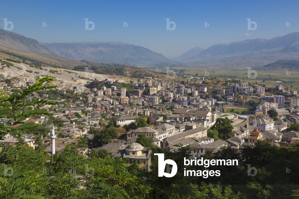 Gjirokastra or Gjirokaster, Albania.  Looking across the typical architecture of the old town to new suburbs beyond. Gjirokastra is a UNESCO World Heritage Site. (photo)