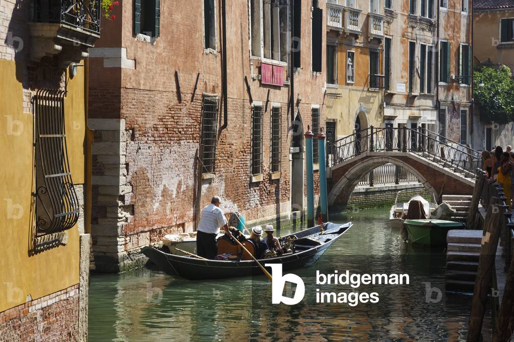 Venice, Italy.  Tourists enjoying gondola ride on canal. (photo)