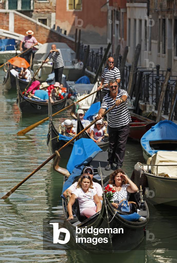 Venice, Venice Province, Veneto, Italy.  Tourists enjoying gondola ride on canal.