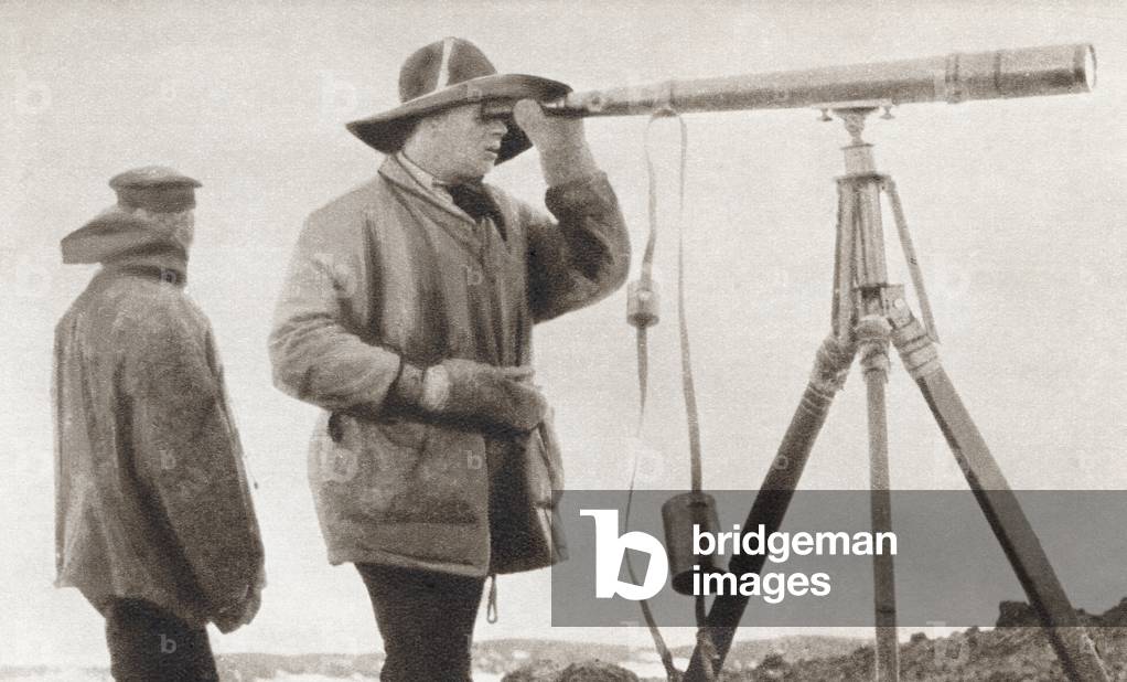 Robert Falcon Scott looking through a telescope during The Terra Nova Expedition to the south pole in 1912. From The Story of 25 Eventful Years in Pictures, published 1935.