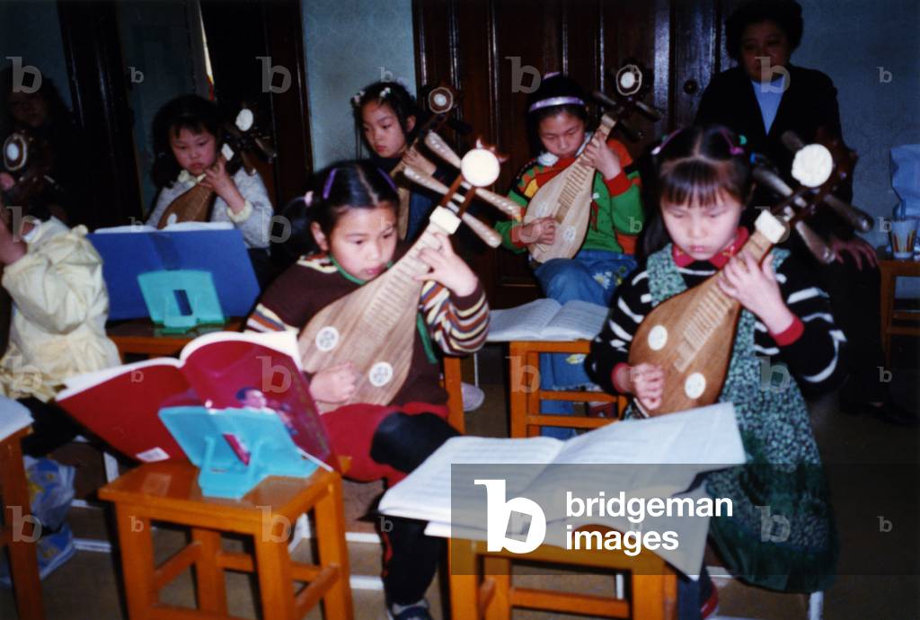 Chinese children playing pipa instruments in classroom