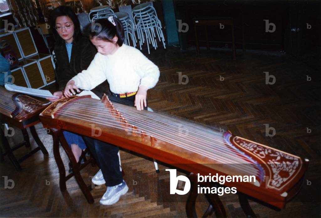 China - Chinese girl playing gu qin (zither) using Chinese musical notation in Shanghai music school