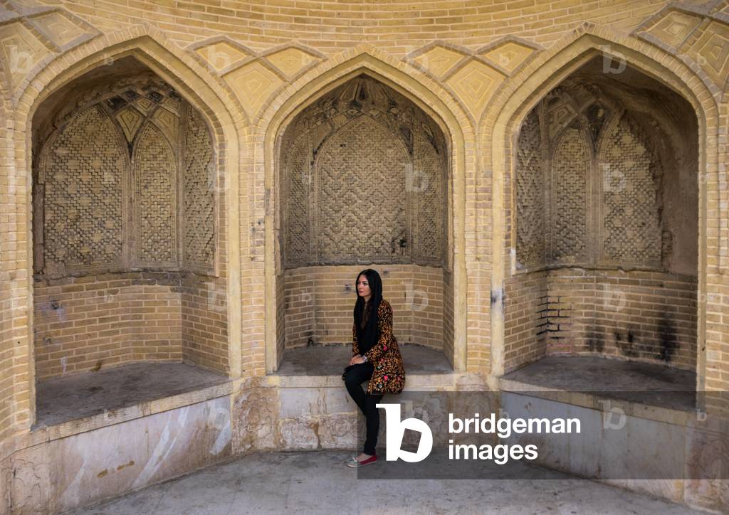 Iranian Veiled Woman Sitting on a Stone Bench, Fars Province, Shiraz, Iran (photo)
