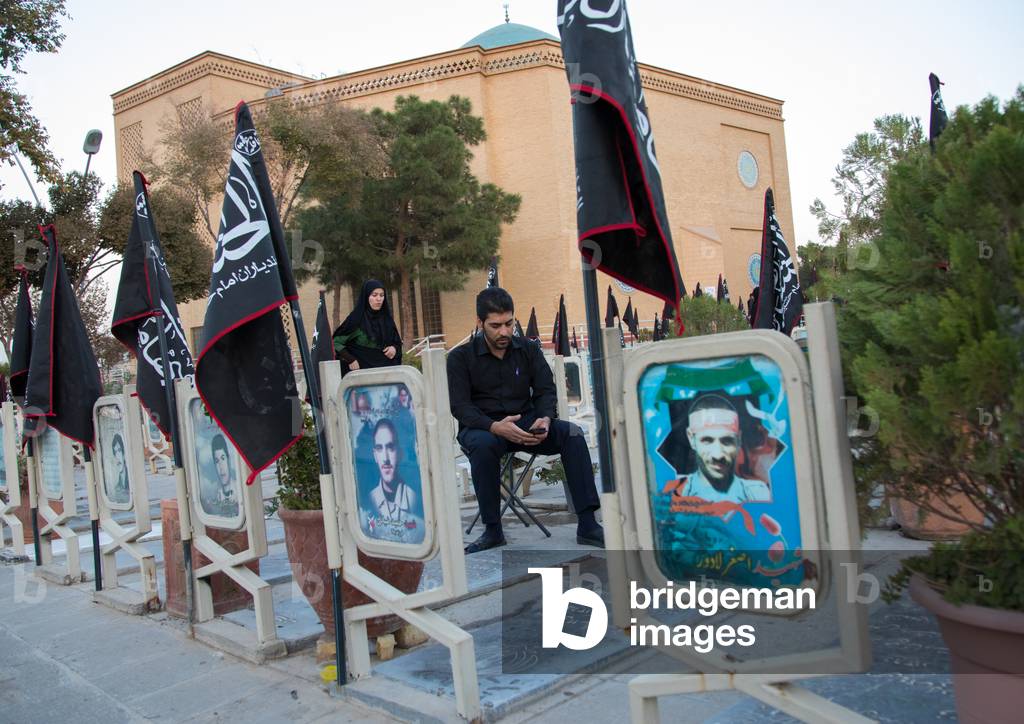 Iranian man praying on the tomb of his relative killed in the Iran Iraq War in the Rose garden of martyrs cemetery, Isfahan Province, Isfahan, Iran (photo)
