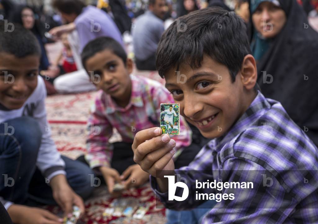Pilgrim child showing a ronaldo sticker at the shrine of fatima al-masumeh, Qom province, Qom, Iran (photo)