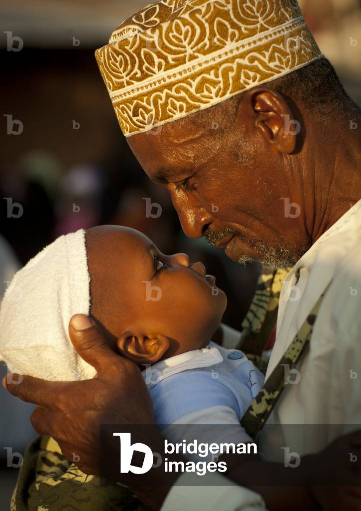 Father carrying small baby  with coaled eyelids during maulidi, Lamu, Kenya, Africa
 (photo)