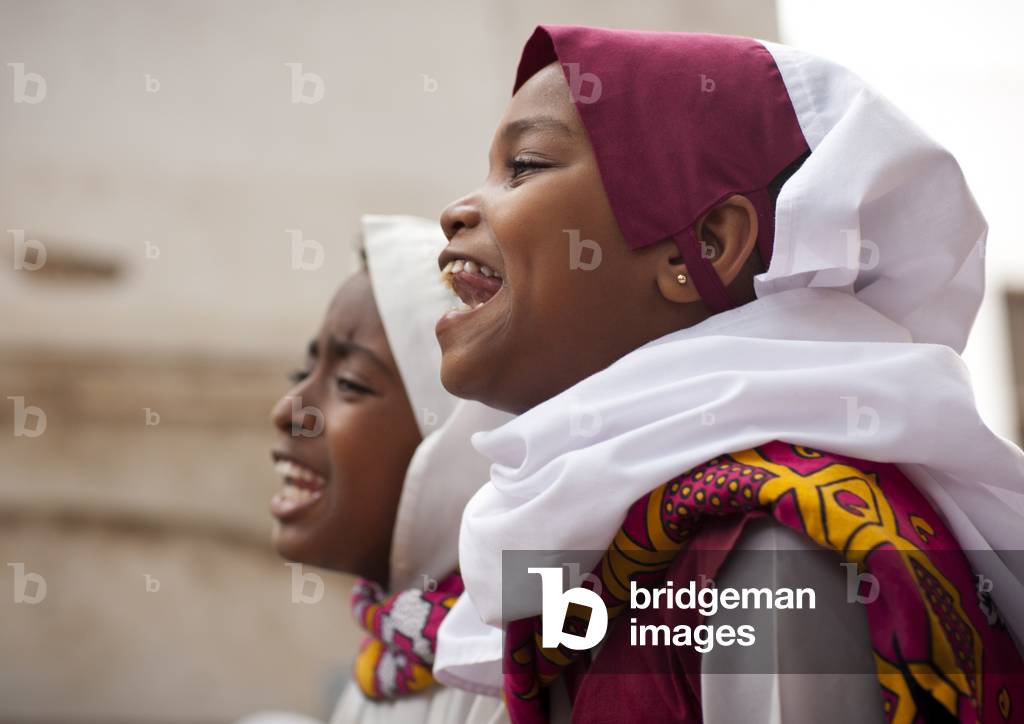 Two young girls singing in traditional suit during maulidi celebration, Lamu Kenya, Africa (photo)