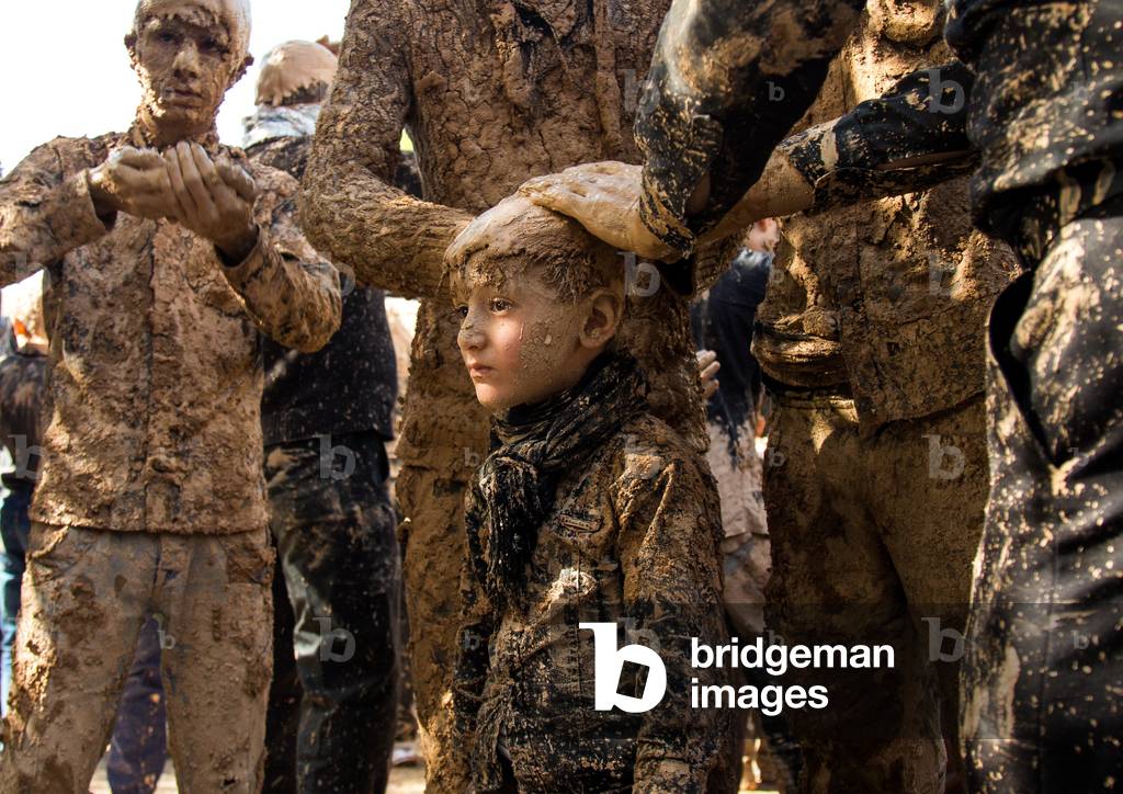 Iranian Shiite Muslim Boy Covered in Mud by Adults during Ashura Day, Kurdistan Province, Bijar, Iran (photo)