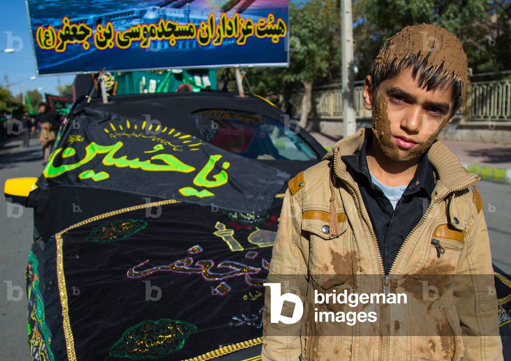 Iranian Shiite Muslim Boy Covered in Mud in front of a Decorated Car during Ashura, Kurdistan Province, Bijar, Iran (photo)