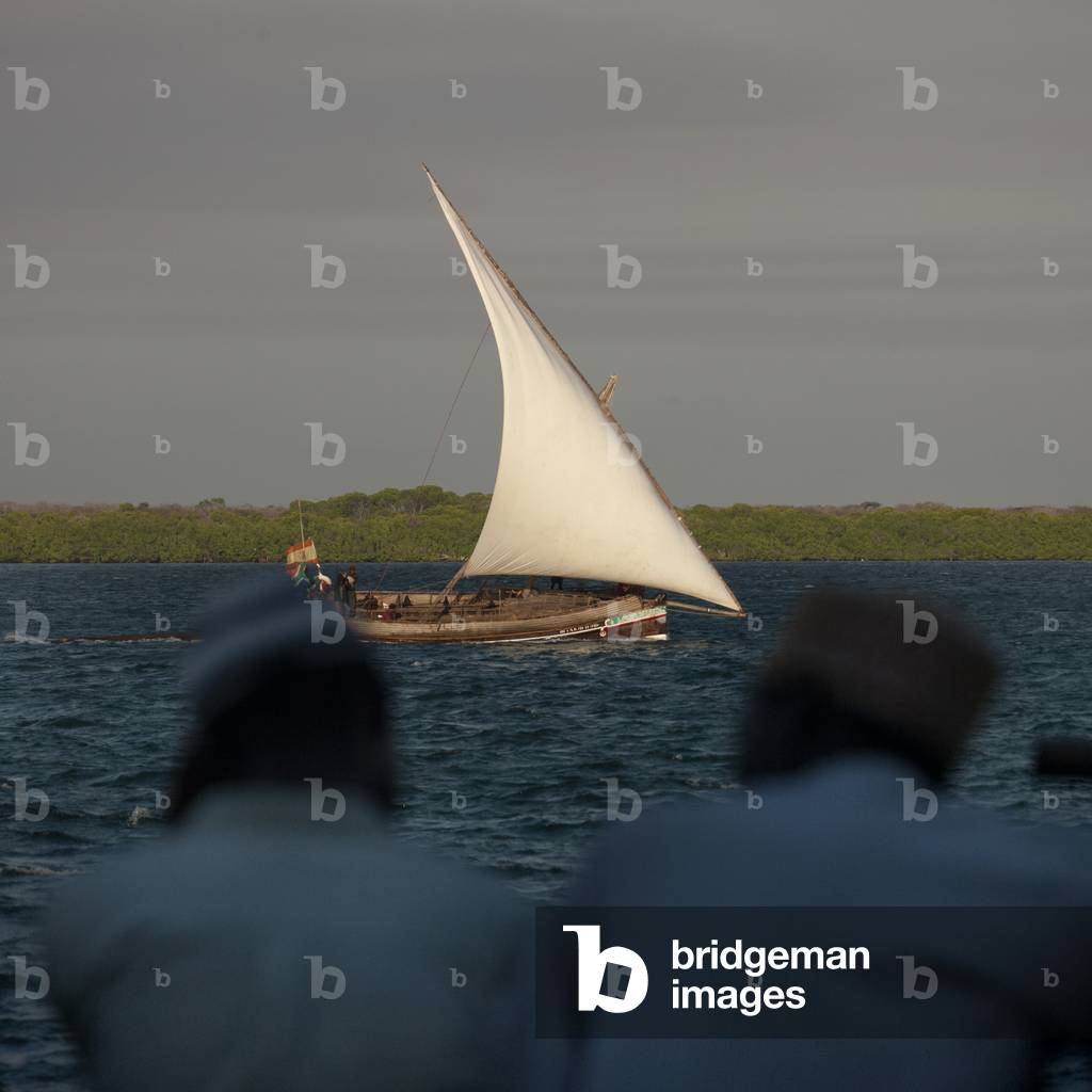 Dhow sailing in channel, Two senior men chatting in foreground, Lamu, Kenya, Africa (photo)