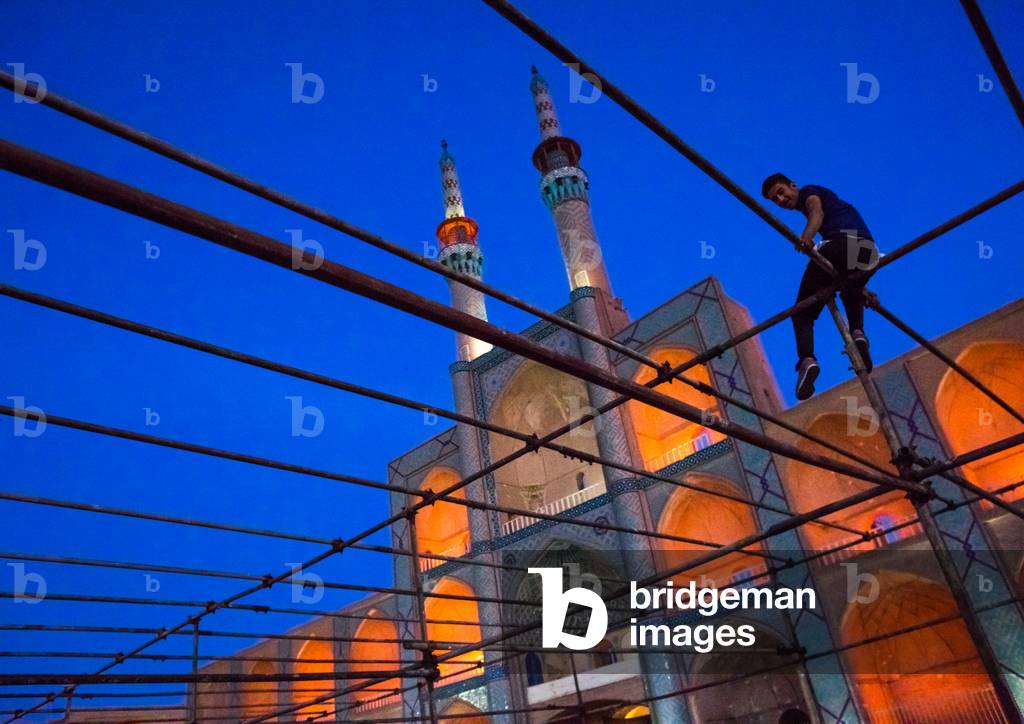 Man Sitting on a Scaffolding in front of the Three-storey Takieh Part of the Amir Chakhmaq Complex, Yazd Province, Yazd, Iran (photo)