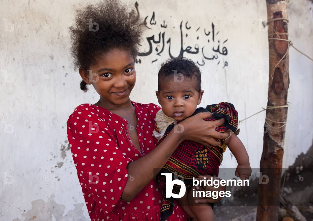 Young girl with baby boy smling at camera, Lamu, Kenya, Africa (photo)