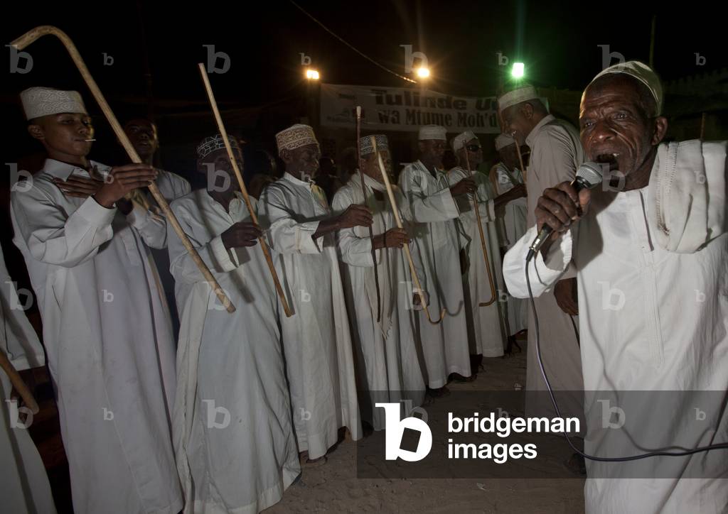 Senior man singing and directing goma stick dance at maulidi festival, Lamu, Kenya, Africa (photo)