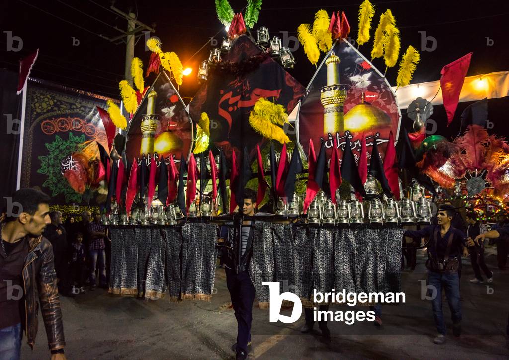 An Iranian Man carrying an Alam helped by Shiite Muslim Mourners, Isfahan Province, Kashan, Iran (photo)
