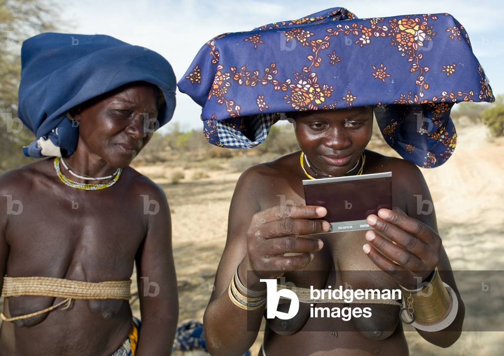 Mukubal Women looking Polaroid Pictures of Themselves, Virie Area, Angola, Africa (photo)