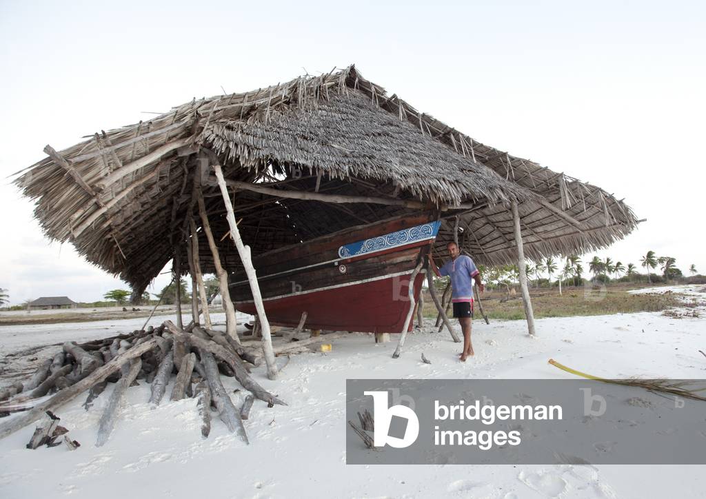 Shipyard on a beach with palm roof, One man standing, Lamu, Kenya, Africa (photo)