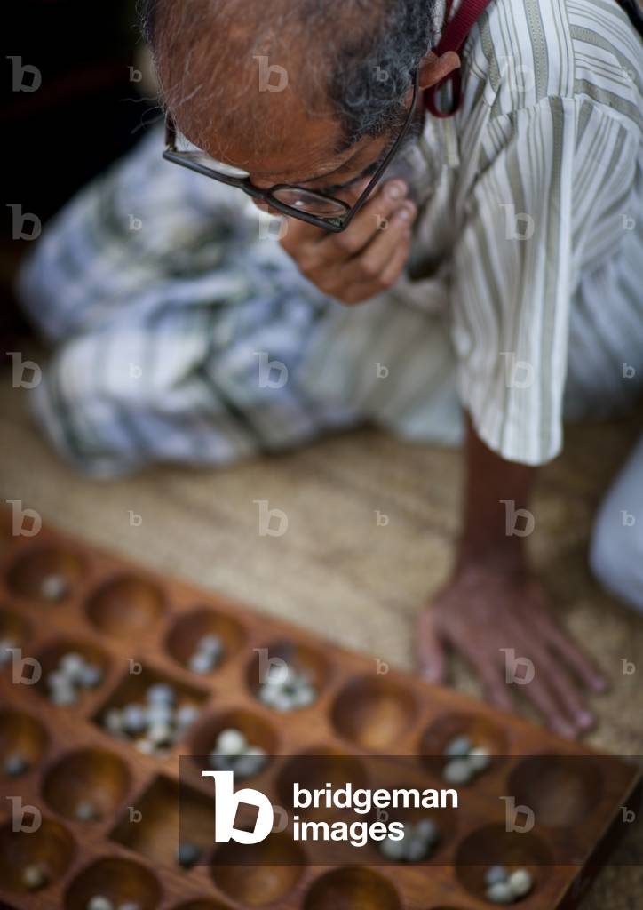 Contemplative player of bao in a street of lamu, During maulidi festival, Lamu, Kenya, Africa (photo)
