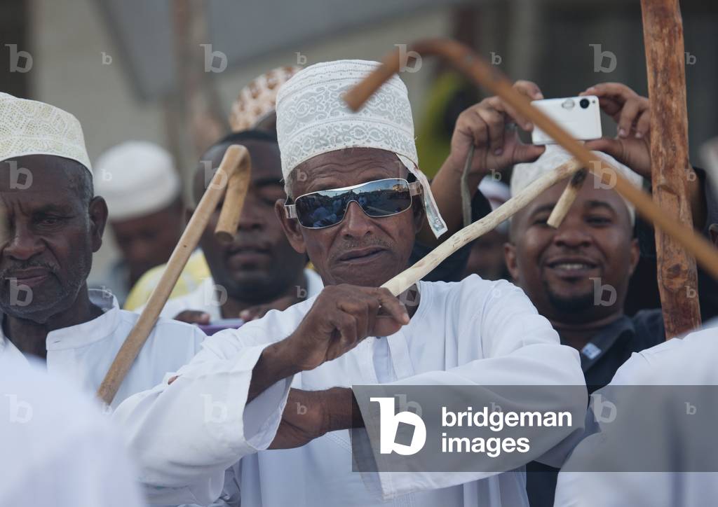Senior man with sunglasses dancing goma stick dance at maulidi festival, Lamu, Kenya, Africa (photo)