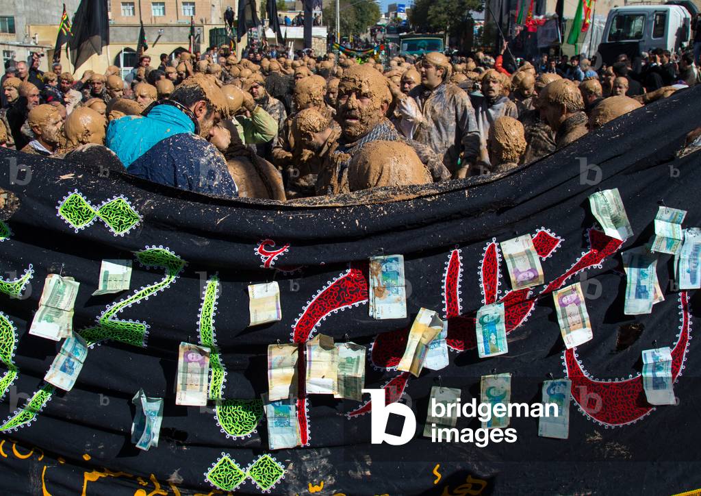 Iranian Shiite Muslim Men Covered in Mud in front of a Flag with Bank Notes Attached during Ashura Day, Kurdistan Province, Bijar, Iran (photo)