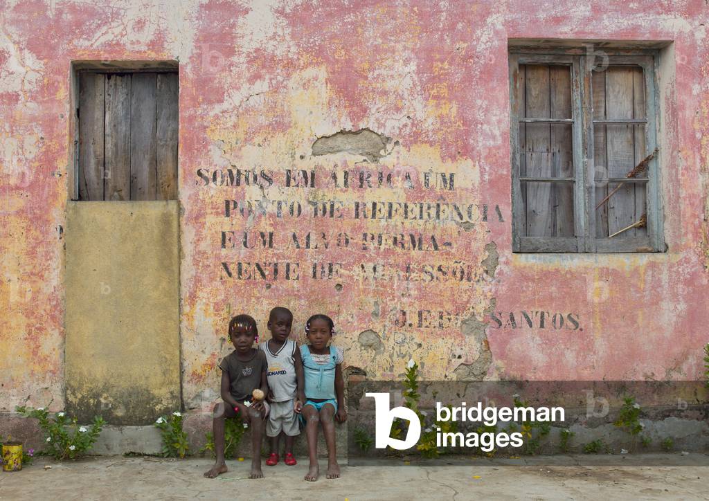 Children in front of an Old Communist Propaganda Message Written on Facade, Bilaiambundo, Angola, Africa (photo)