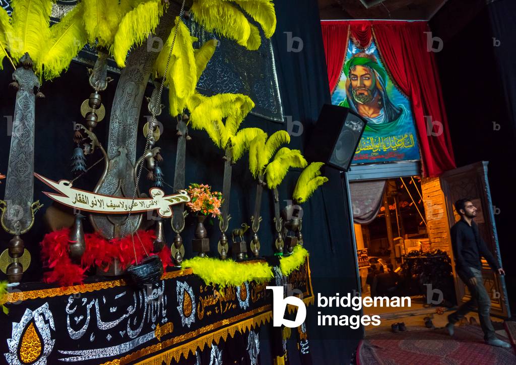 An Alam Near an Imam Hussein Portrait on Ashura, Isfahan Province, Kashan, Iran (photo)